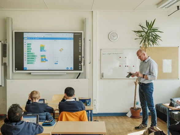 Teacher is showing the class how to write code in a classroom