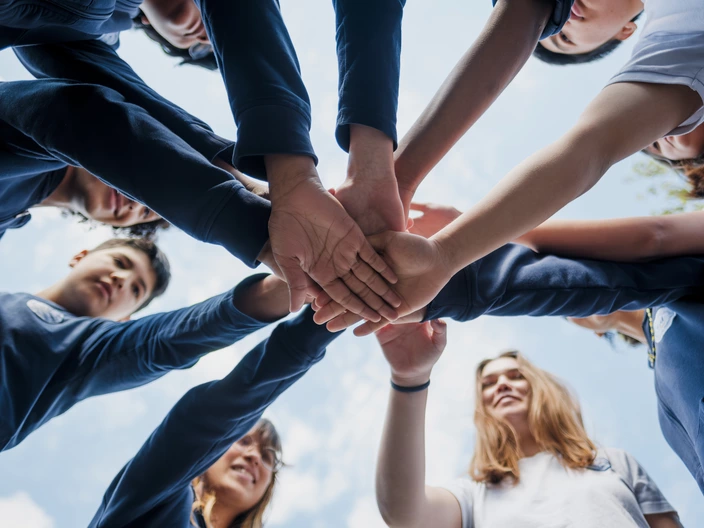 group of students place their hands in a circle on top of each other's hands